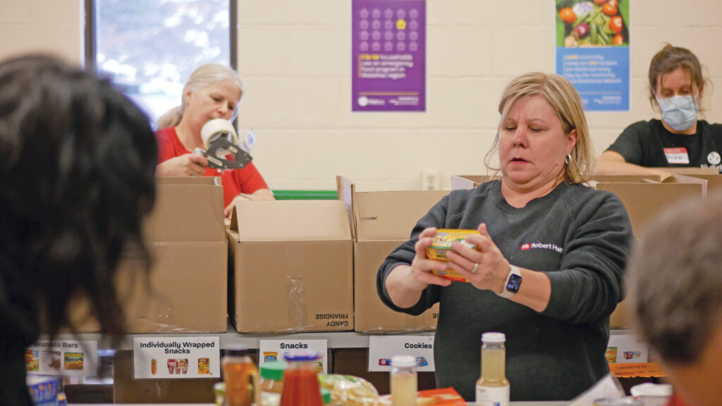Robert Half team sorting, inspecting and taping up boxes full of non-perishable food.