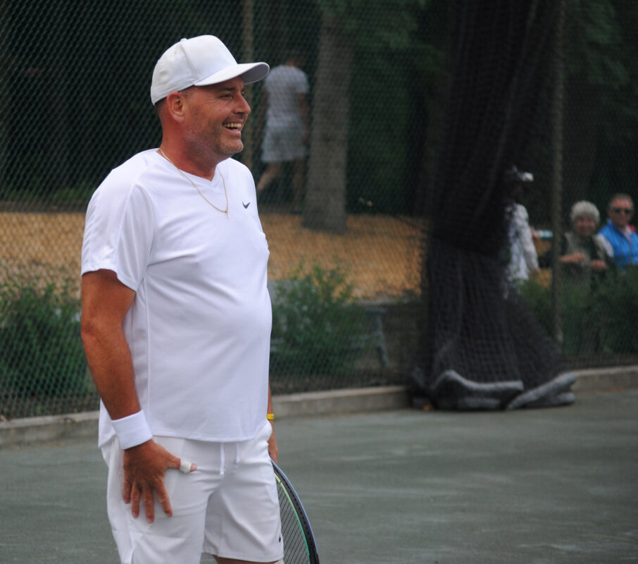 Man holding a tennis racket smiling.
