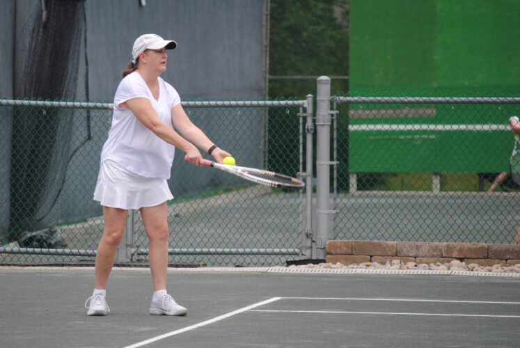A woman getting ready to serve a tennis ball.
