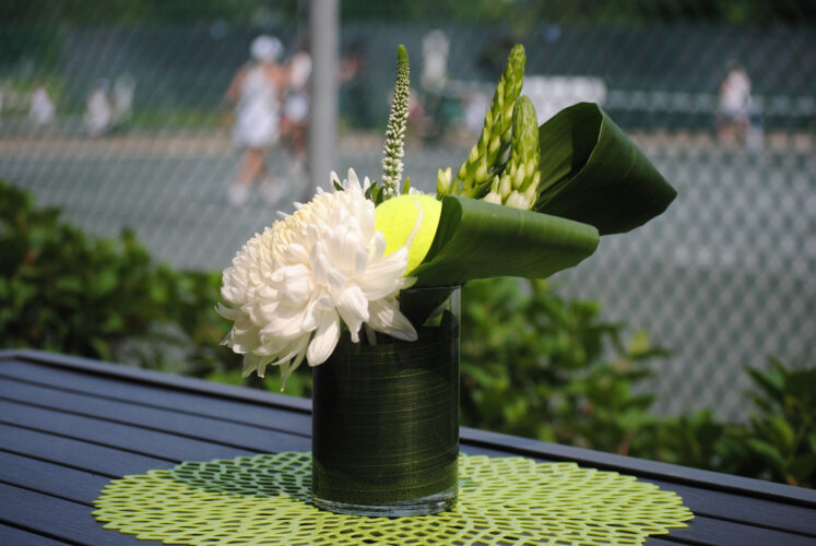 Flower decoration with people playing tennis in the background.