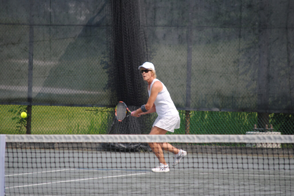 Woman about to hit a tennis ball coming at her.