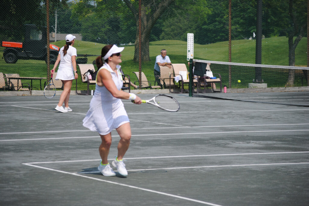 A woman pivoting into position ready to hit a tennis ball.