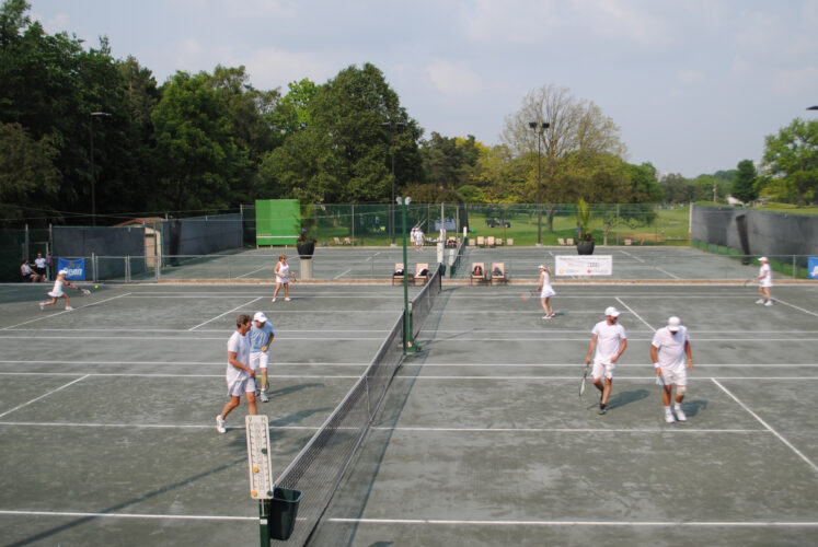 A panoramic photo of people playing tennins.