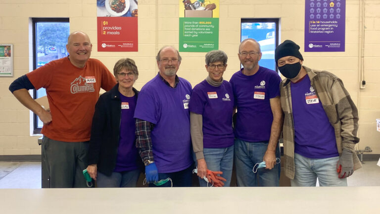 Food Bank of Waterloo Region volunteers standing shoulder to shoulder smiling
