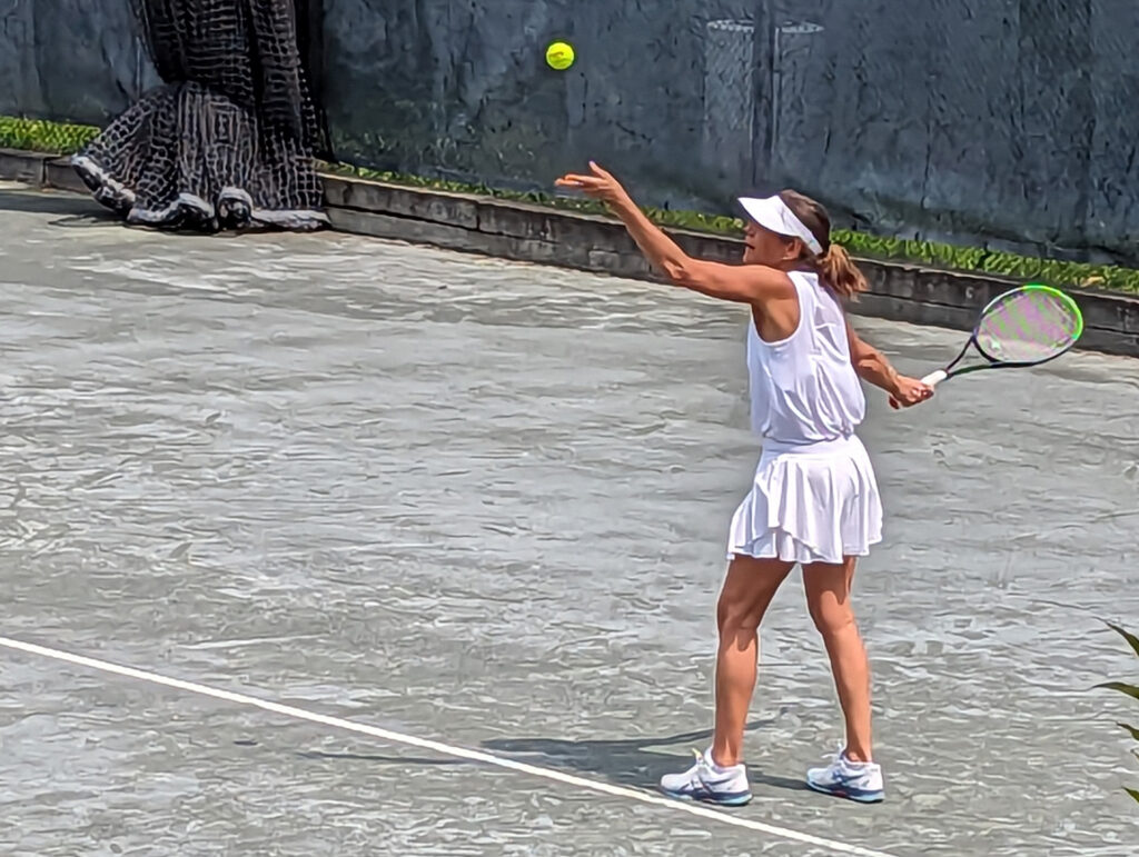 Woman playing tennis about to serve.