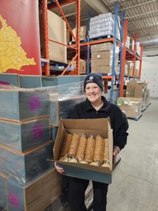 Sara Melo, our warehouse lead hand, is holding a box of crackers donated by RDJ Bakeries.