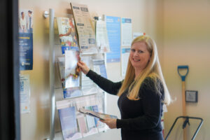 Michelle Rickard placing our Community Impact report in The Food Bank’s vestibule.