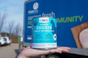 MCC Ontario’s canned chicken held up by the Food Bank of Waterloo region's truck.
