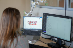 Emily looking at a desktop screen which displays the logo for Fight for a Cause
